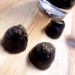 three dark chocolate truffles loose on wood