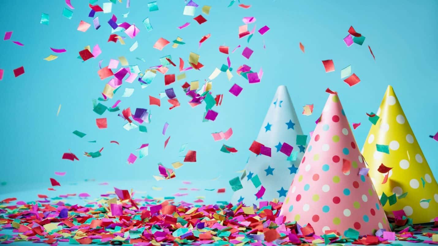 party hats and confetti over blue background